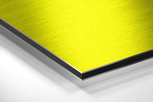 Angled perspective view of stacked brushed aluminum sheets showing bright yellow top surface with black and gray layers beneath.