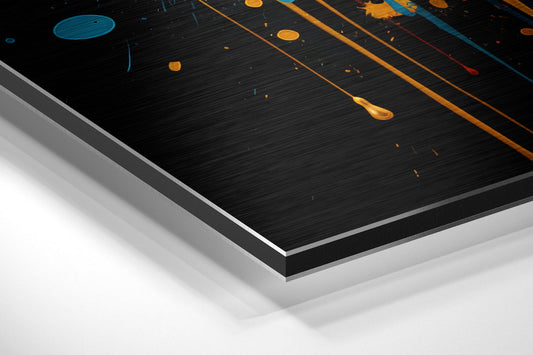 Close-up angled view of layered aluminum dibond panel showing black brushed surface with gold paint drips and blue accents.