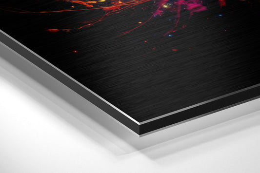 Angled edge-on view of brushed aluminum dibond panel showing colorful planets and paint splash design against black surface with white base layer visible.