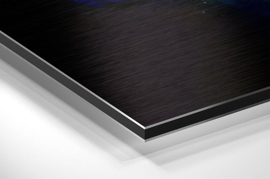 Close-up angled view of layered Dibond panel showing black brushed aluminum top surface with gray and white composite layers beneath.