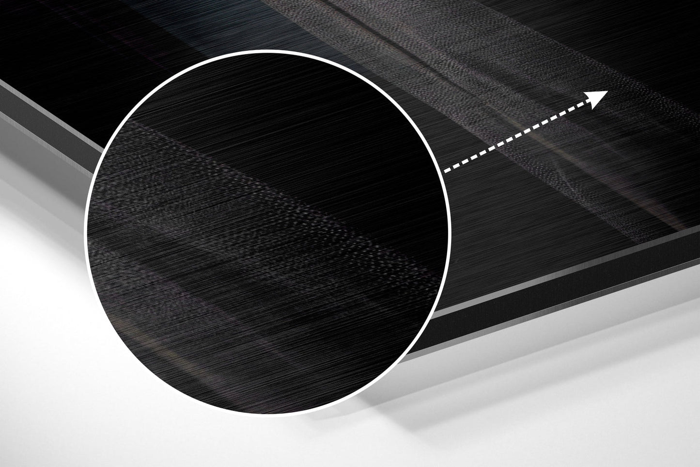 Close-up angled view of brushed aluminum Dibond wall art showing circular black textured center with white border and directional arrow detail.