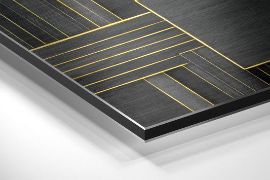 Angled perspective view of black brushed aluminum panel with gold geometric line pattern on white background.