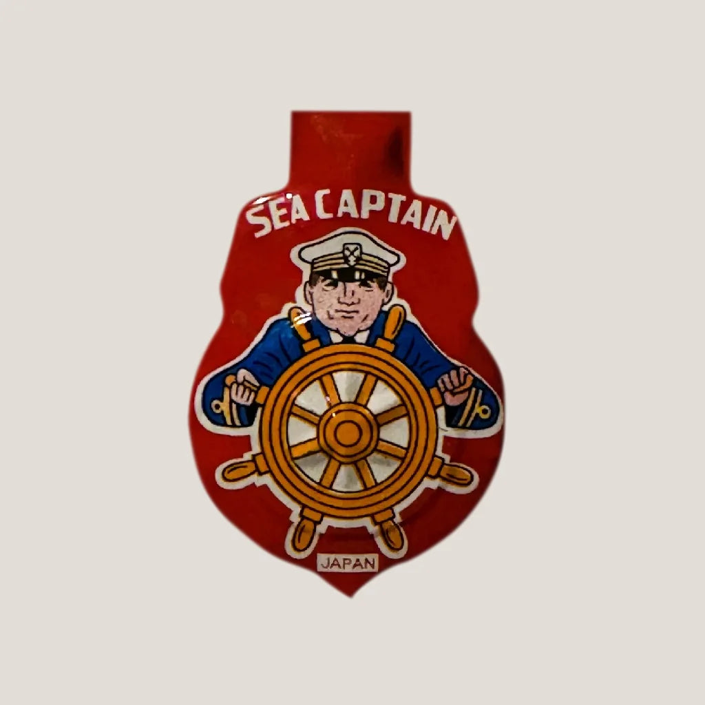 Red sea captain bottle opener on 1960s sea captain tin clicker whistle surface