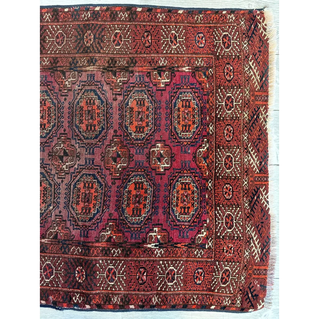 Antique 1910s tribal Turkoman rug detail showing dense geometric gul patterns in crimson red and blue