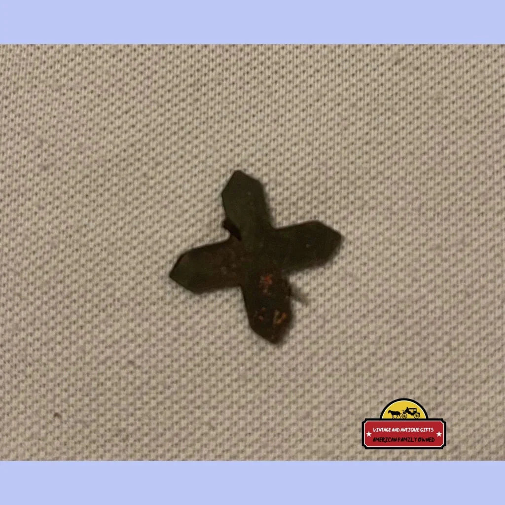 Cross-shaped dark antique vintage Thrasher Tin Tobacco Tag on textured surface