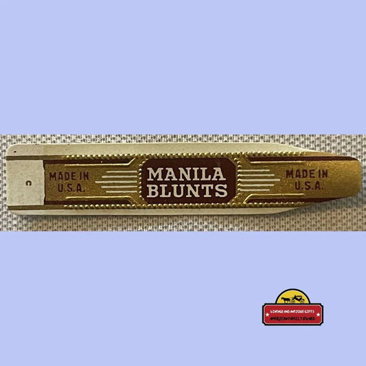 Antique Manila Blunts cigar band in gilt gold foil, maroon center panel reading MANILA BLUNTS with MADE IN U.S.A. on each wing