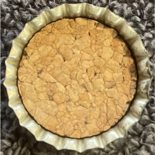 Baked pie with golden crust in fluted dish next to Vintage 1960s Pequot bottle cap