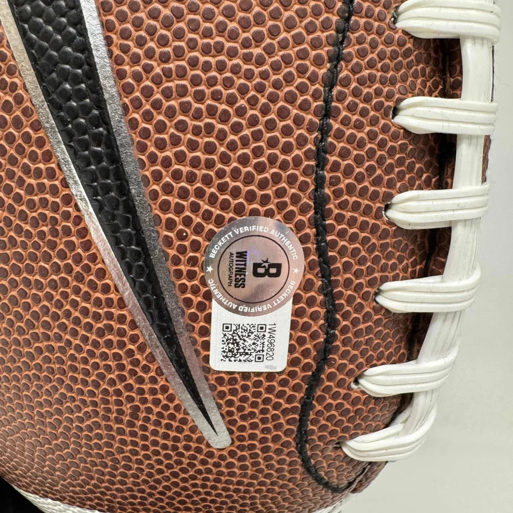Textured brown leather football with white laces and authenticity sticker on display stand