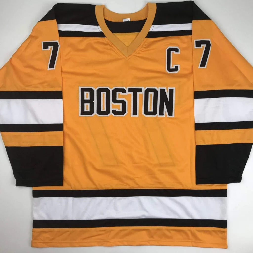 Gold hockey jersey with black and white stripes and number seven for professional sports league fans