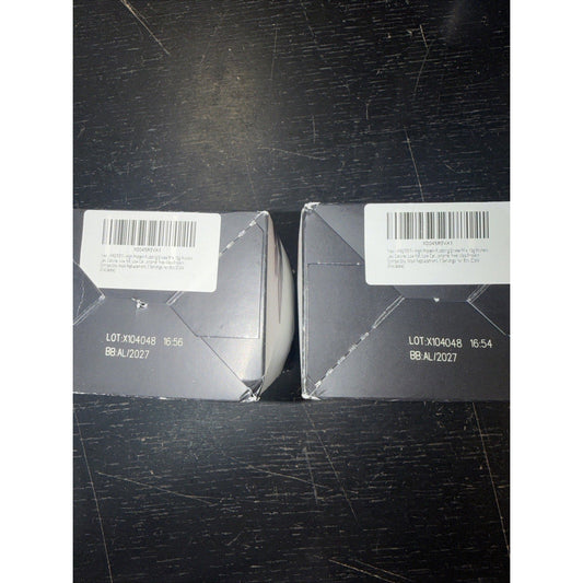 Two gray boxes with white barcode labels and lot information displayed side-by-side on dark scratched surface.