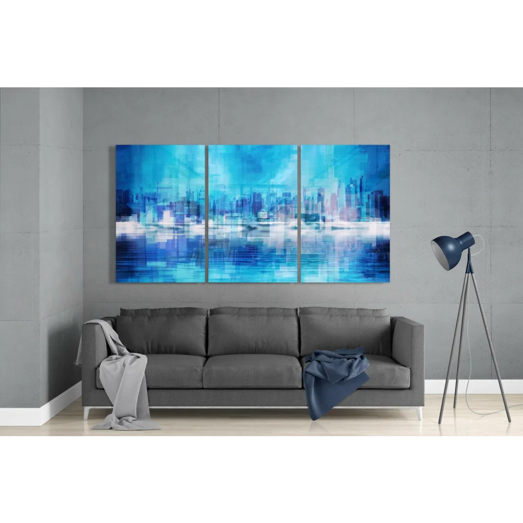 Blue abstract cityscape glass wall art triptych above gray sofa