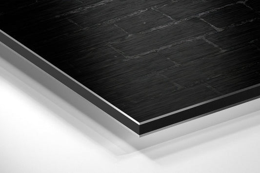 Close-up angled view of layered material composition showing black brushed aluminum surface with gray and white backing layers.