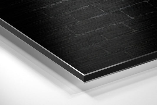 Close-up angled view of layered brushed aluminum and black composite material showing edge detail and surface texture.
