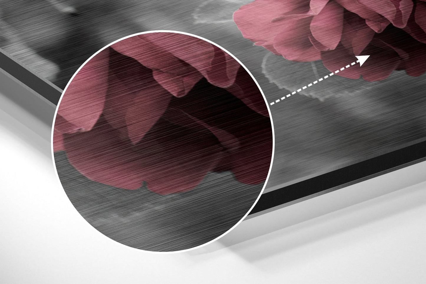 Close-up detail of brushed aluminium surface with pink rose petals and magnified circular view showing texture.