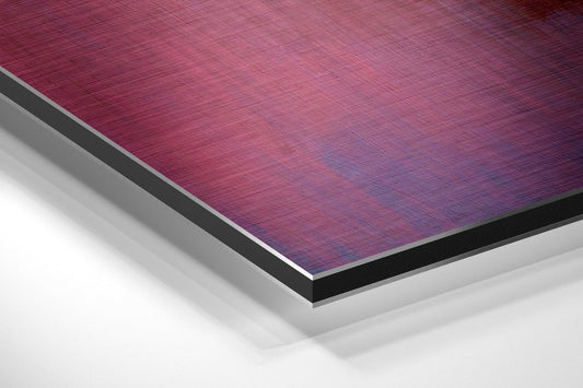 Close-up angled view of layered aluminum dibond panel showing purple-to-pink gradient brushed metal surface with white and black edge borders.