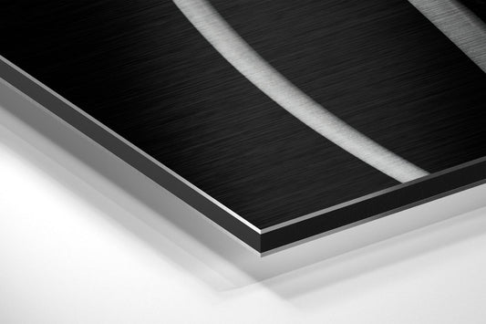 Close-up angled view of layered brushed aluminum and black Dibond panel edges showing metallic surface texture and depth.