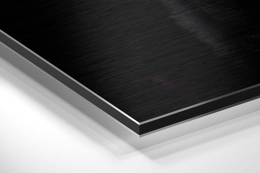 Close-up angled view of layered brushed black and white aluminum composite material showing edge detail and surface texture.