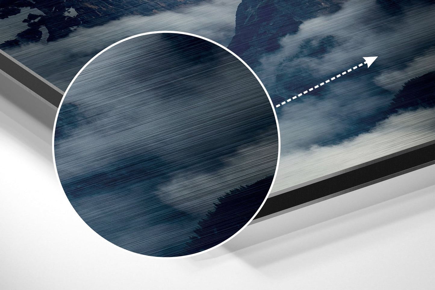 Close-up detail shot of brushed aluminum surface with directional arrow and layered mountain landscape in blue and white tones.