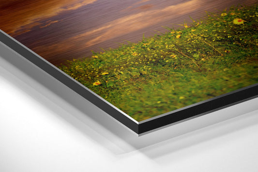 Close-up angled view of layered metal frame showing black border, white spacer, and brushed aluminum backing with nature scene visible on surface.