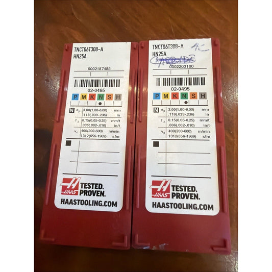Two red plastic cases with white label inserts displaying TNCT06T308-A HN25A specifications and barcodes, shown from above on brown surface.