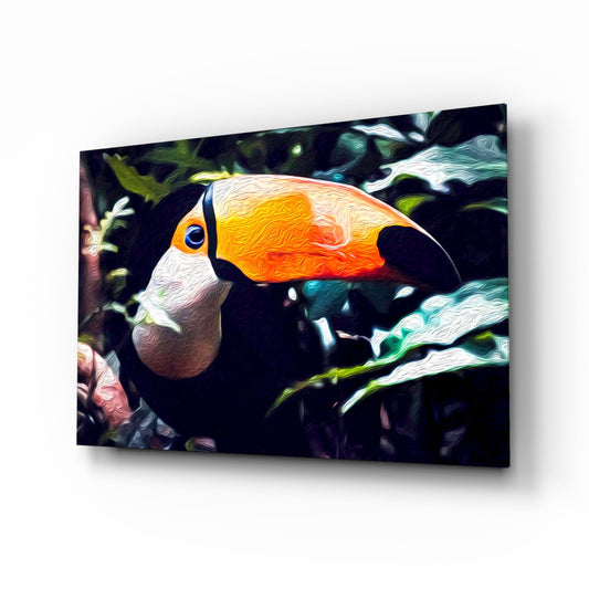 Toco toucan glass wall art displayed at an angle, showing vibrant orange and yellow beak with white and black plumage against a dark foliage background.