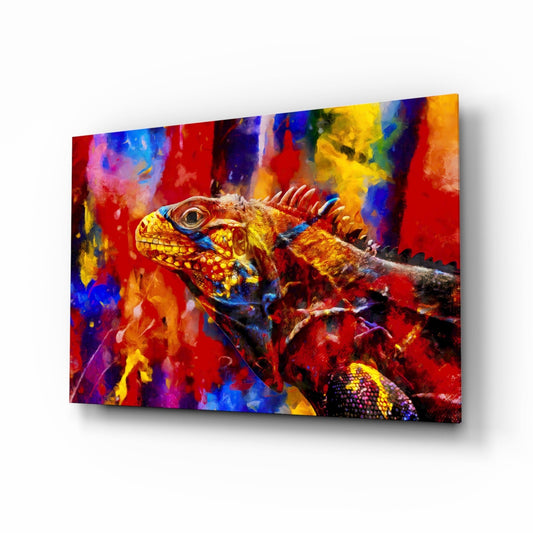 Angled perspective of a glass wall art panel featuring a colorful iguana with vibrant red, yellow, blue, and purple paint splash background.