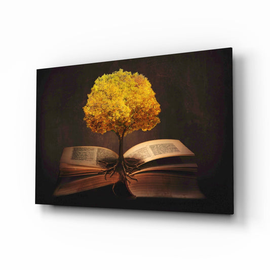 Glass wall art showing a golden tree with glowing foliage growing from an open book against dark background.