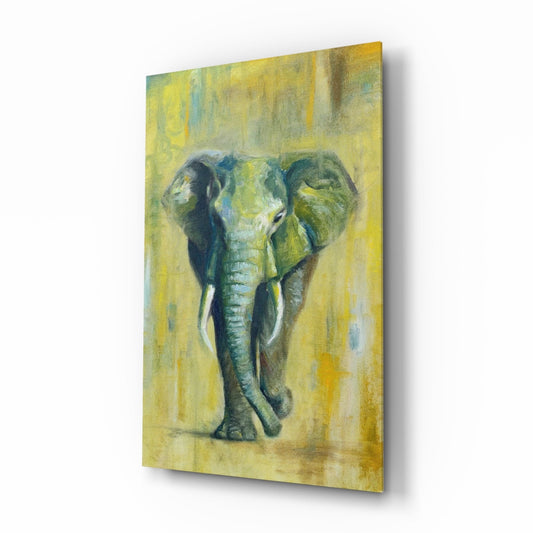 Glass wall art displaying a front-facing green elephant with ivory tusks against a muted yellow background, shown at an angle.