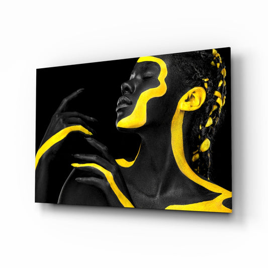 Angled view of glass wall art featuring a woman's profile with black and yellow geometric paint design on dark background.