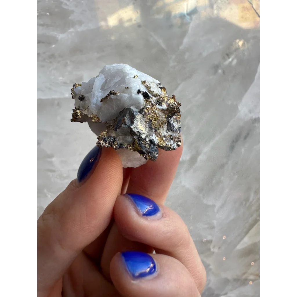 Hand with blue nails holds crystalline gold quartz from 16 to 1 Mine