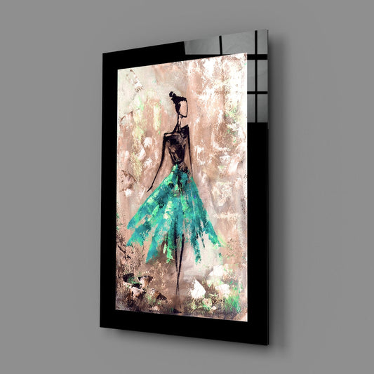 Black-framed glass wall art displaying stylized female figure with teal skirt against weathered textured background, angled perspective view.