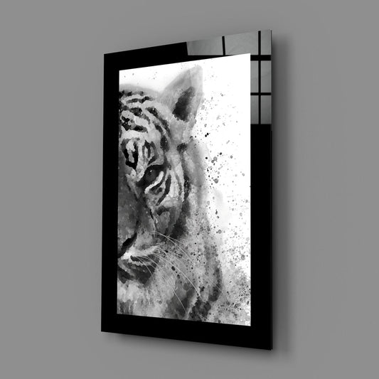 Black-framed glass wall art displaying a monochromatic watercolor tiger profile with splatter effects, mounted at an angle against gray wall.