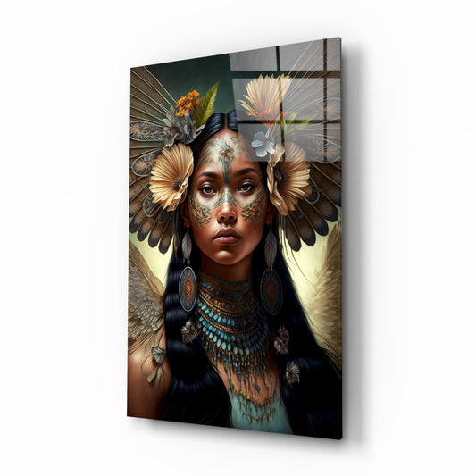Glass wall art panel depicting a woman with facial tattoos, turquoise beaded necklace, and large feathered wings adorned with flowers, photographed at an angle against white background.
