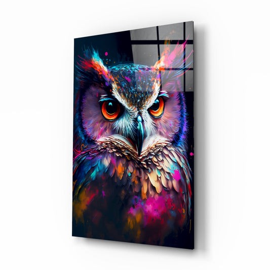 Angled view of a glass wall art panel displaying a vibrant neon owl with glowing orange eyes and multicolored feathers in purple, blue, and magenta tones.