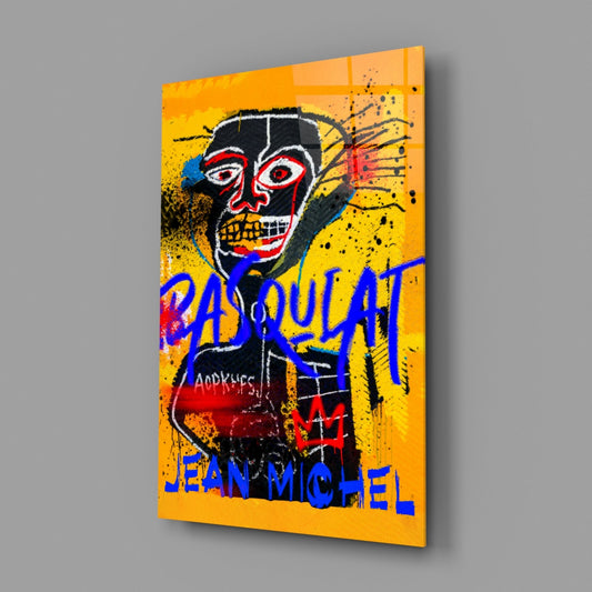 Yellow glass wall art panel displaying black tribal mask with red eyes, blue and red text reading "BASQUIAT" and "JEAN-MICHEL," shown at an angle against gray background.