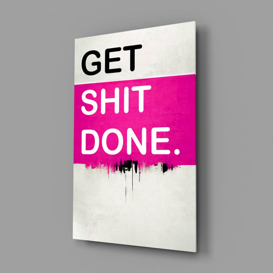 Angled view of glass wall art with white background, hot pink horizontal band, and black text reading "GET SHIT DONE." with dripping paint effect.