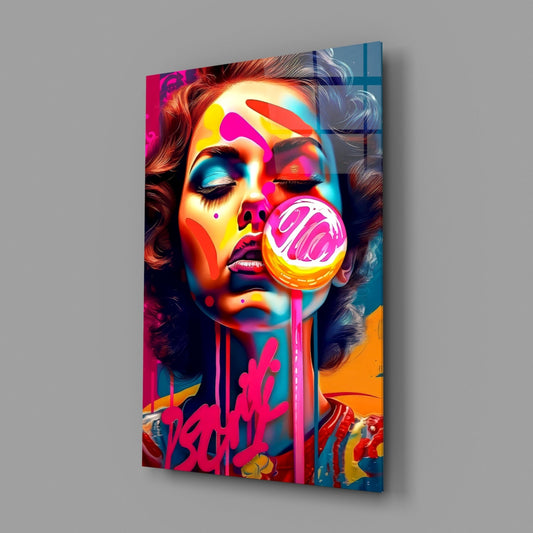 Angled view of glass wall art featuring a colorful portrait of a woman with a pink lollipop, vibrant neon colors, and graffiti elements against a gray background.