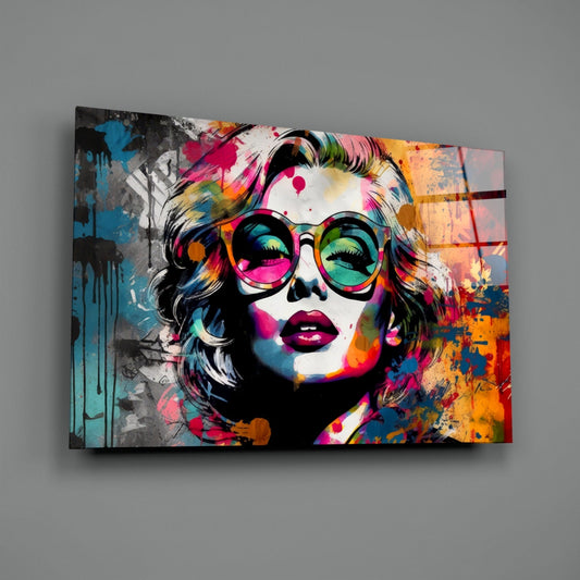 Colorful pop art glass wall panel featuring a portrait with round tortoiseshell glasses against vibrant splashes of pink, blue, orange, and yellow.
