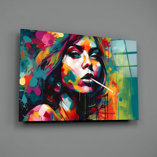 Colorful abstract portrait of a woman with a lollipop on glass wall art, displayed at an angled perspective against a gray wall.