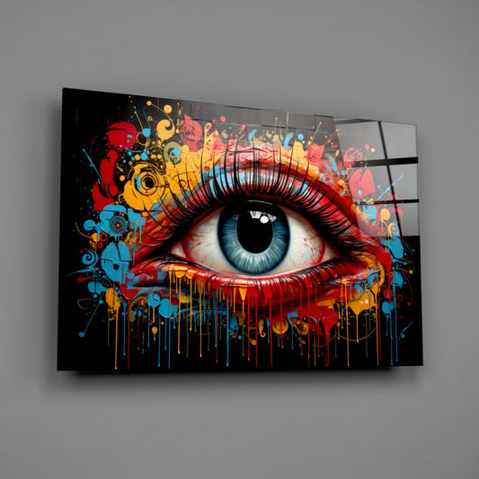 Angled view of glass wall art displaying a stylized eye with blue iris, red and yellow paint splatters, and dripping effects on black background.