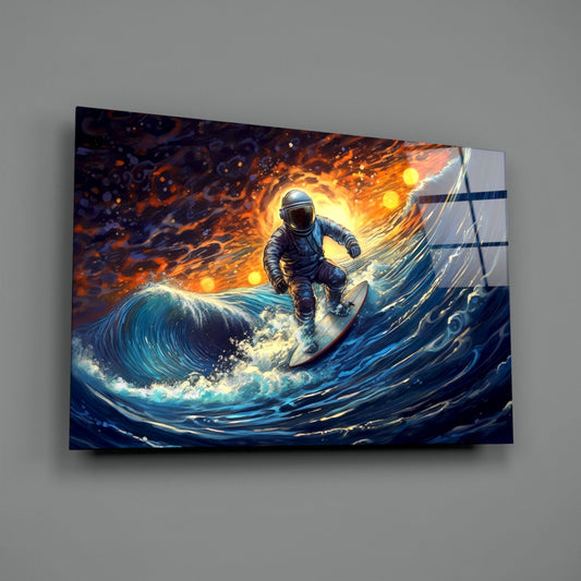 Glass wall art panel displaying an astronaut surfing on a luminous blue wave against an orange and gold fiery sky background, mounted on a gray wall.