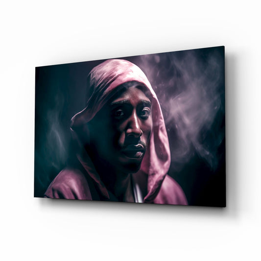 Glass wall art displaying a portrait of a person wearing a pink hood against a dark teal and smoky background, shown at an angle.