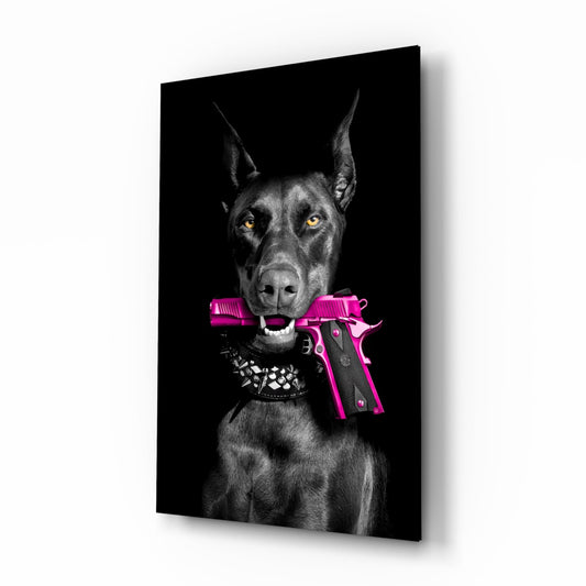 Black and white Doberman with pointed ears and yellow eyes holding a bright pink pistol in its mouth, wearing a studded collar, against black background on glass panel.