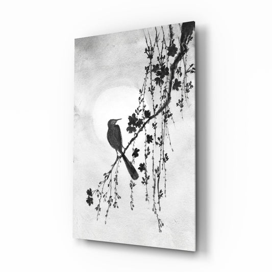 Black and white glass wall art displaying a silhouetted bird perched on a drooping flowering branch against a light background, photographed at an angle showing the panel's depth and shadow.