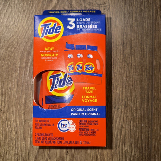 Tide liquid detergent travel size box displaying front packaging with orange and blue colors, three pouches visible inside window, on wooden surface.