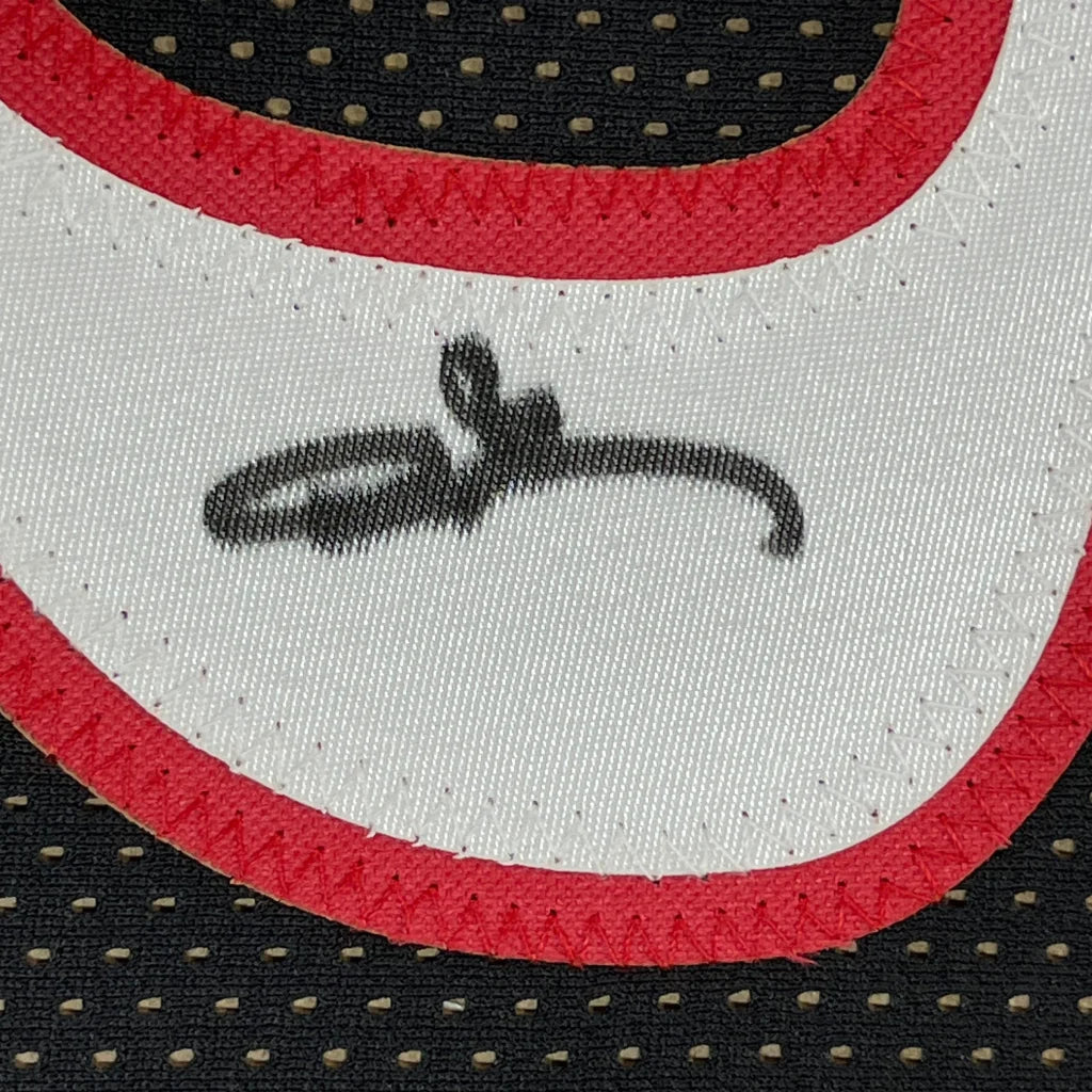 White fabric with red trim and black autograph on framed Allen Iverson jersey with photos