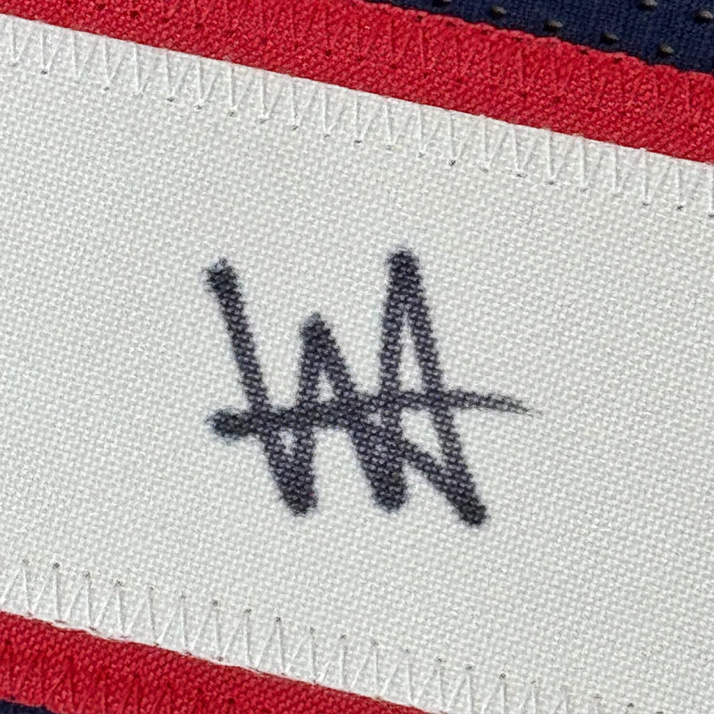 White fabric label with black stylized wa logo stitched on a framed autographed houston blue football jersey