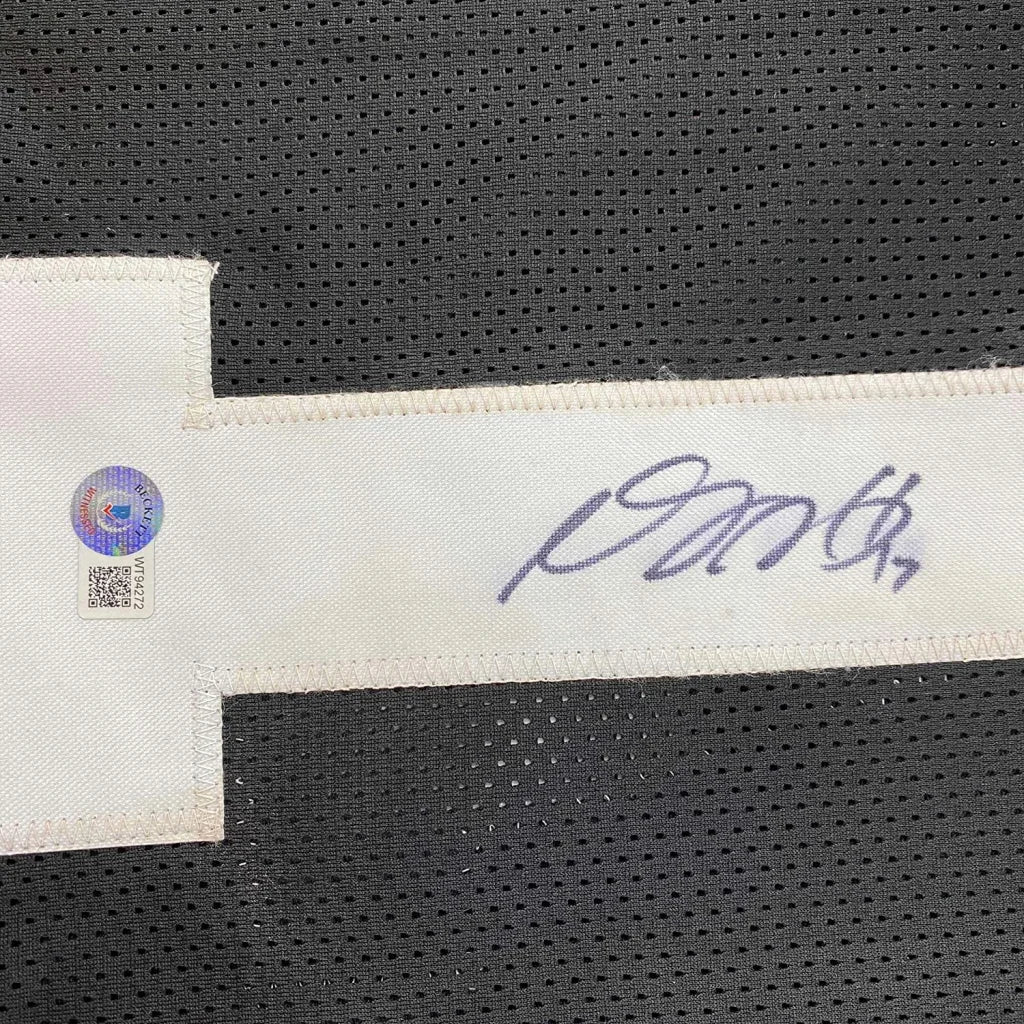 A white fabric tag with signature and authentication sticker attached to black perforated mesh on las vegas oakland football jersey