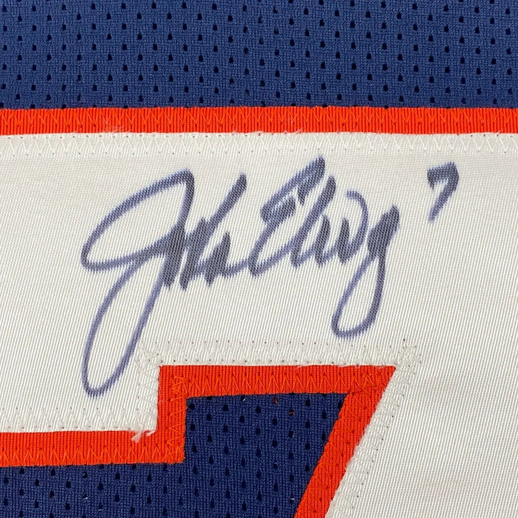Framed autographed white and blue denver football jersey with orange trim signed above number 7 by john elway