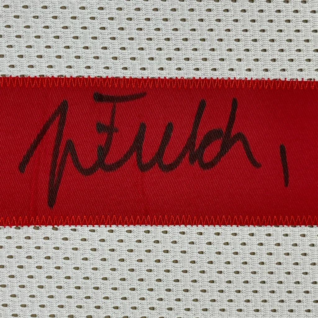 A red fabric strip with a black signature stitched on ohio state white perforated mesh football jersey